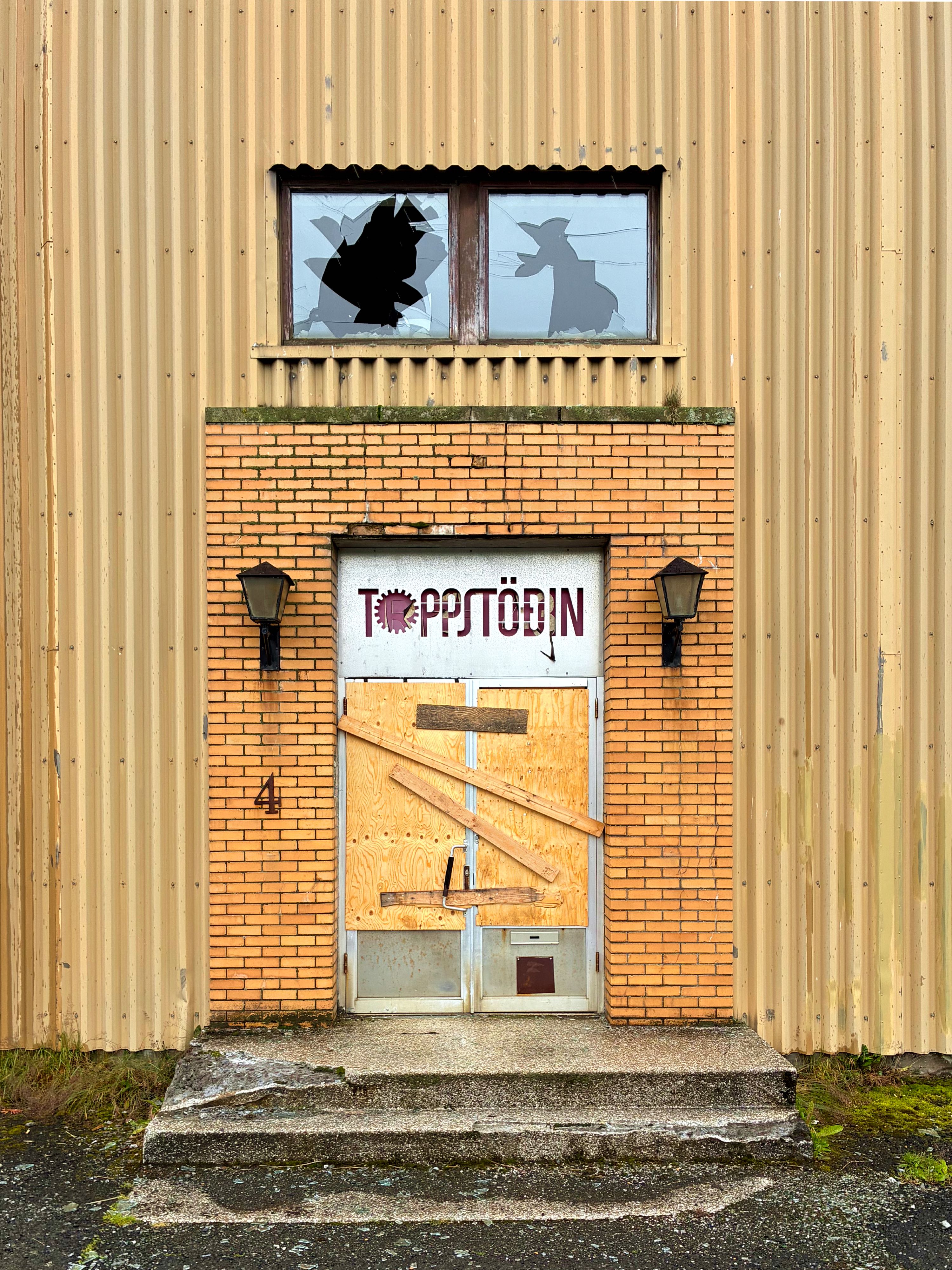 The door to an abandoned power station with broken windows.
