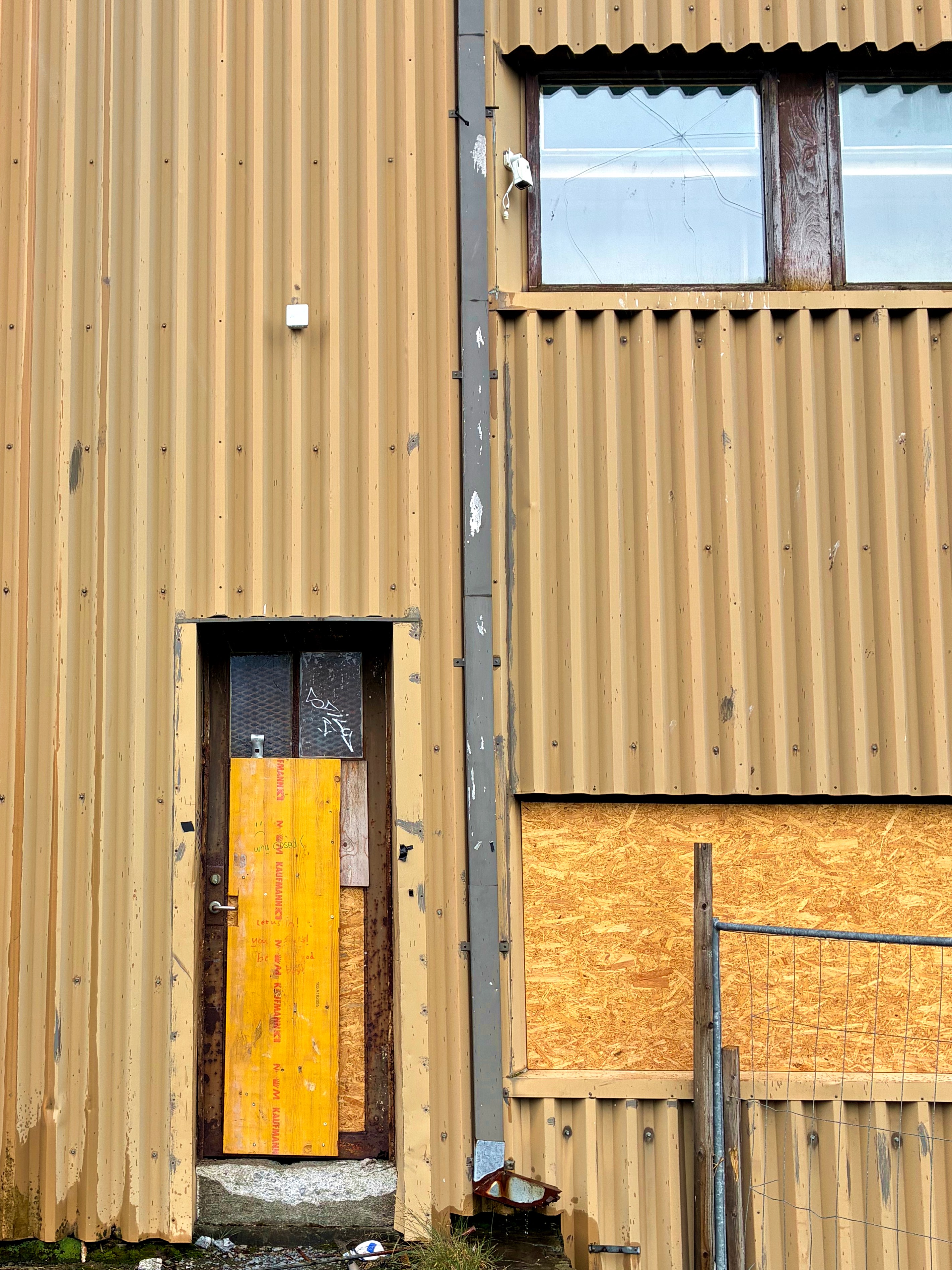 A boarded up door and windows on an abandoned building.