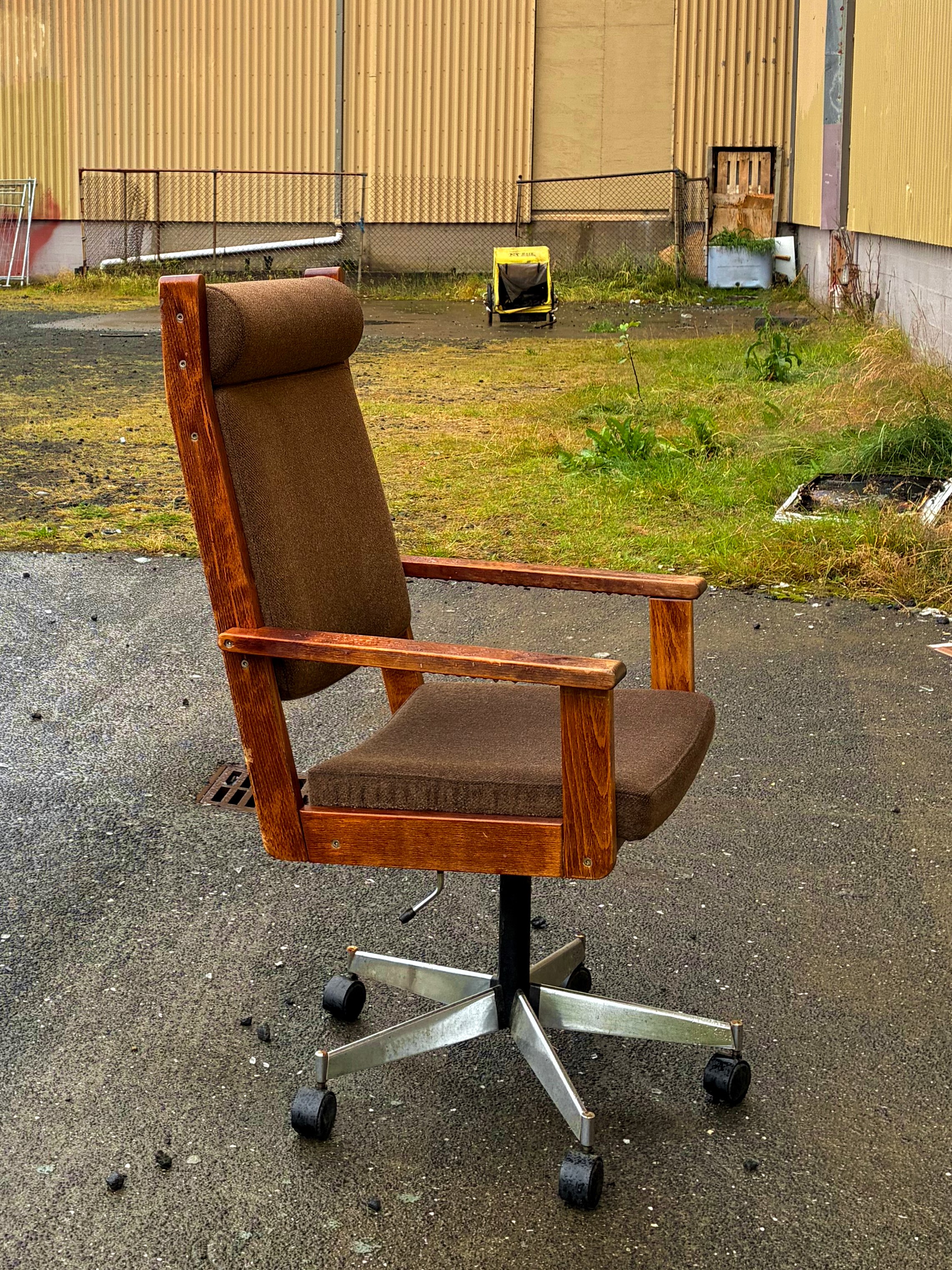 An old office chair outside of an abandoned building.